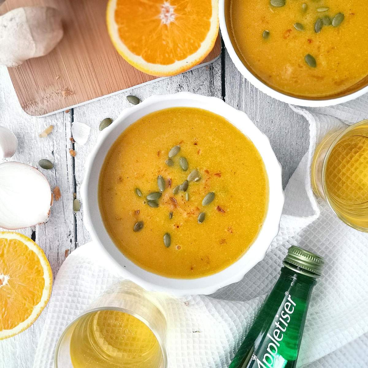 A bowl of creamy coconut curry soup on a white table.