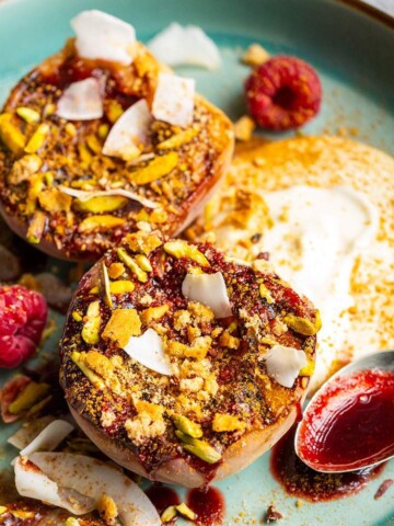 Grilled balsamic peaches with coconut yogurt and raspberry coulis on a dessert plate.