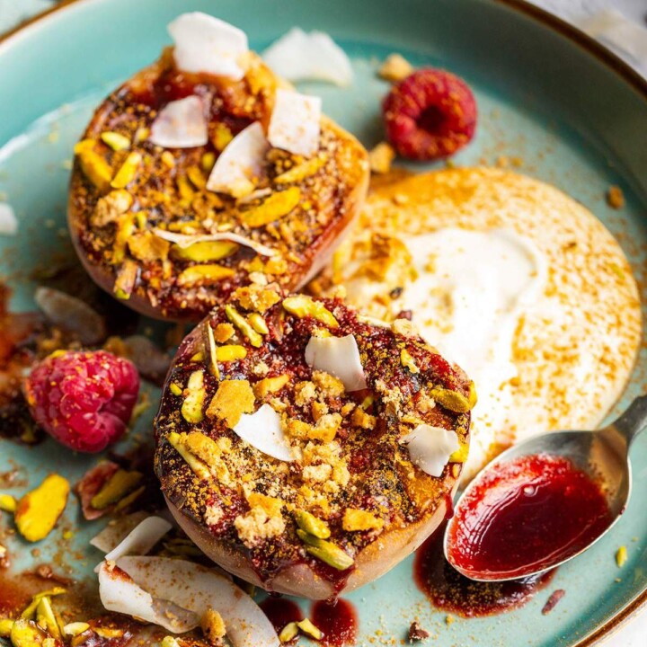Grilled balsamic peaches with coconut yogurt and raspberry coulis on a dessert plate.