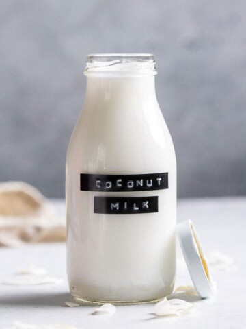 Homemade coconut milk in a glass bottle with a label.