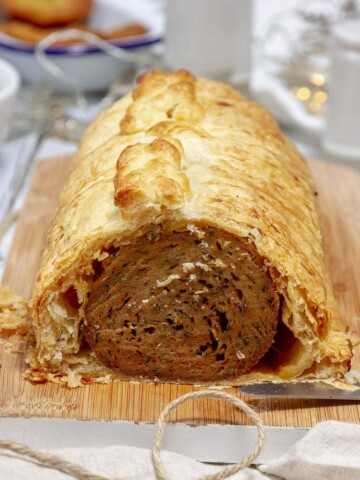 A vegan Seitan wellington on a serving board on the dinner table.