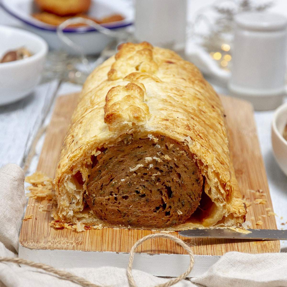 Festive Vegan Seitan Wellington Recipe A vegan Seitan wellington on a serving board on the dinner table.