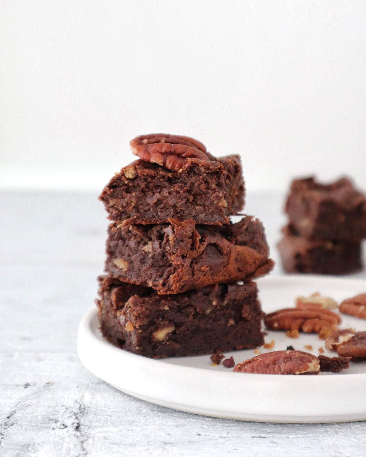 3 vegan keto brownies stacked on a plate.