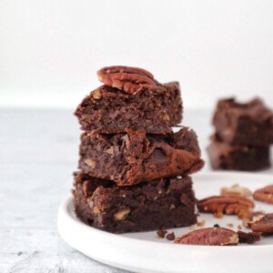 3 vegan keto brownies stacked on a plate.