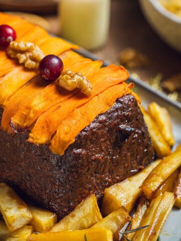 A vegan lentil and walnut nut roast decorated with carrot slices.