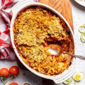 A casserole dish filled with vegan pasta bake and a serving spoon on the side.