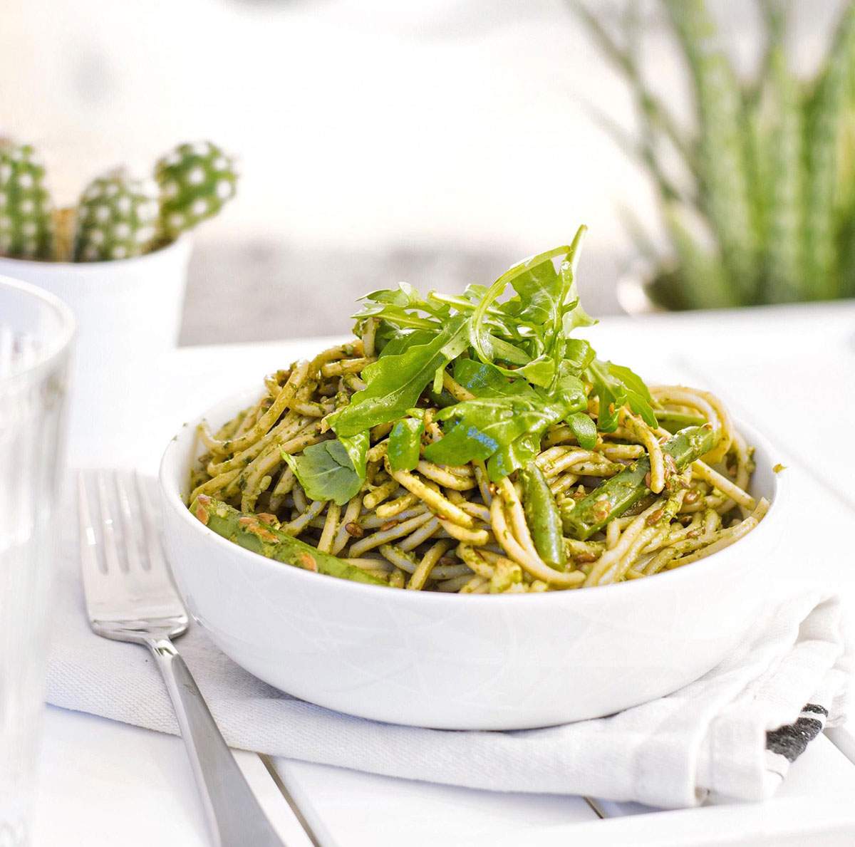 Easy Vegan Pasta Recipe A bowl of green vegan spinach pasta with fresh arugula on top.