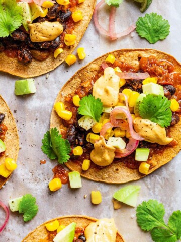 Vegan tostadas with black beans, sweetcorn, salsa, pickled onions, cilantro and vegan nacho cheese sauce.