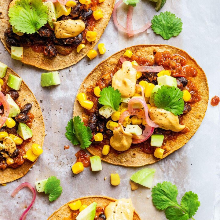 Vegan tostadas with black beans, sweetcorn, salsa, pickled onions, cilantro and vegan nacho cheese sauce.