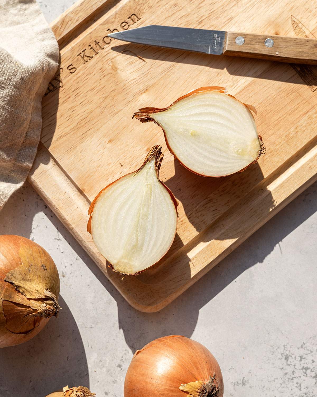 Two onion halves on a wooden board showing the clean, white interior.