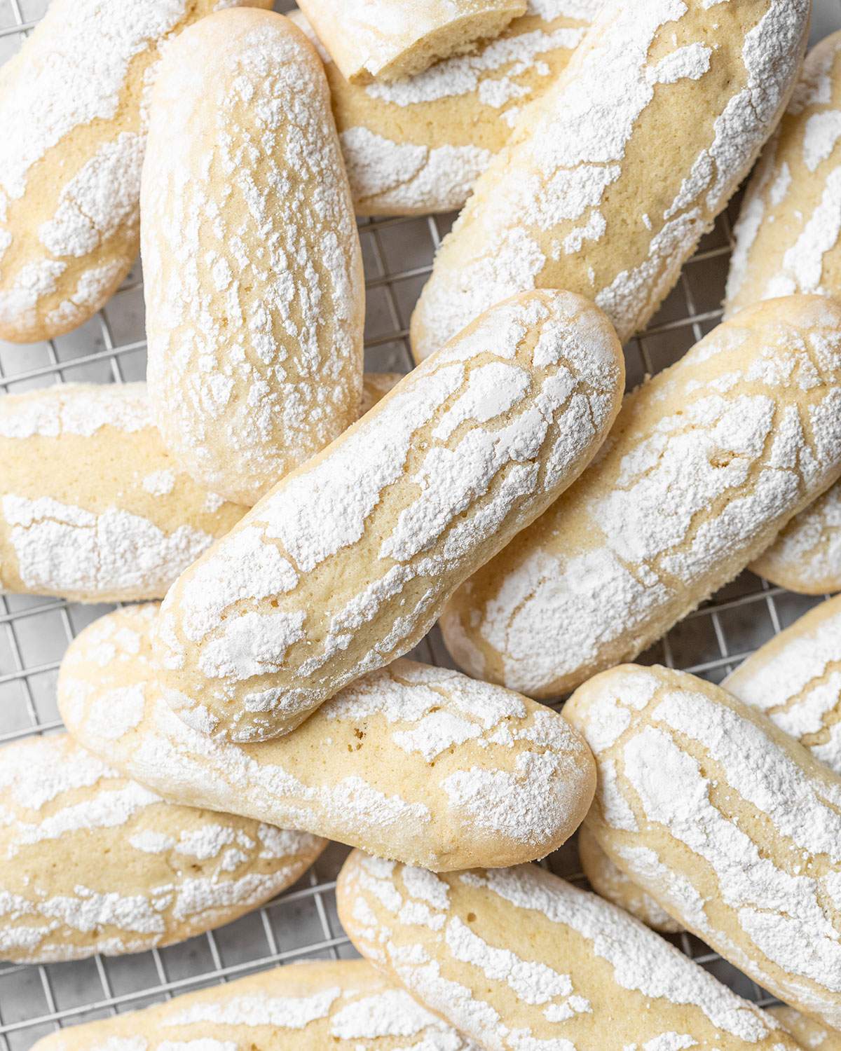 A couple of Vegan ladyfinger biscuits dusted with icing sugar piled on top of each other.