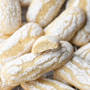 Vegan ladyfinger cookies up close and a broken cookie on top showing the buttery texture.