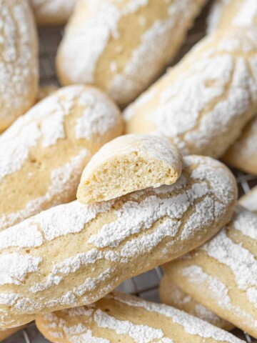 Vegan ladyfinger cookies up close and a broken cookie on top showing the buttery texture.