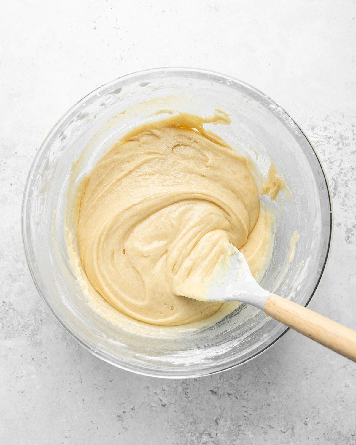 Batter for ladyfinger cookies with a spatula in a mixing bowl.