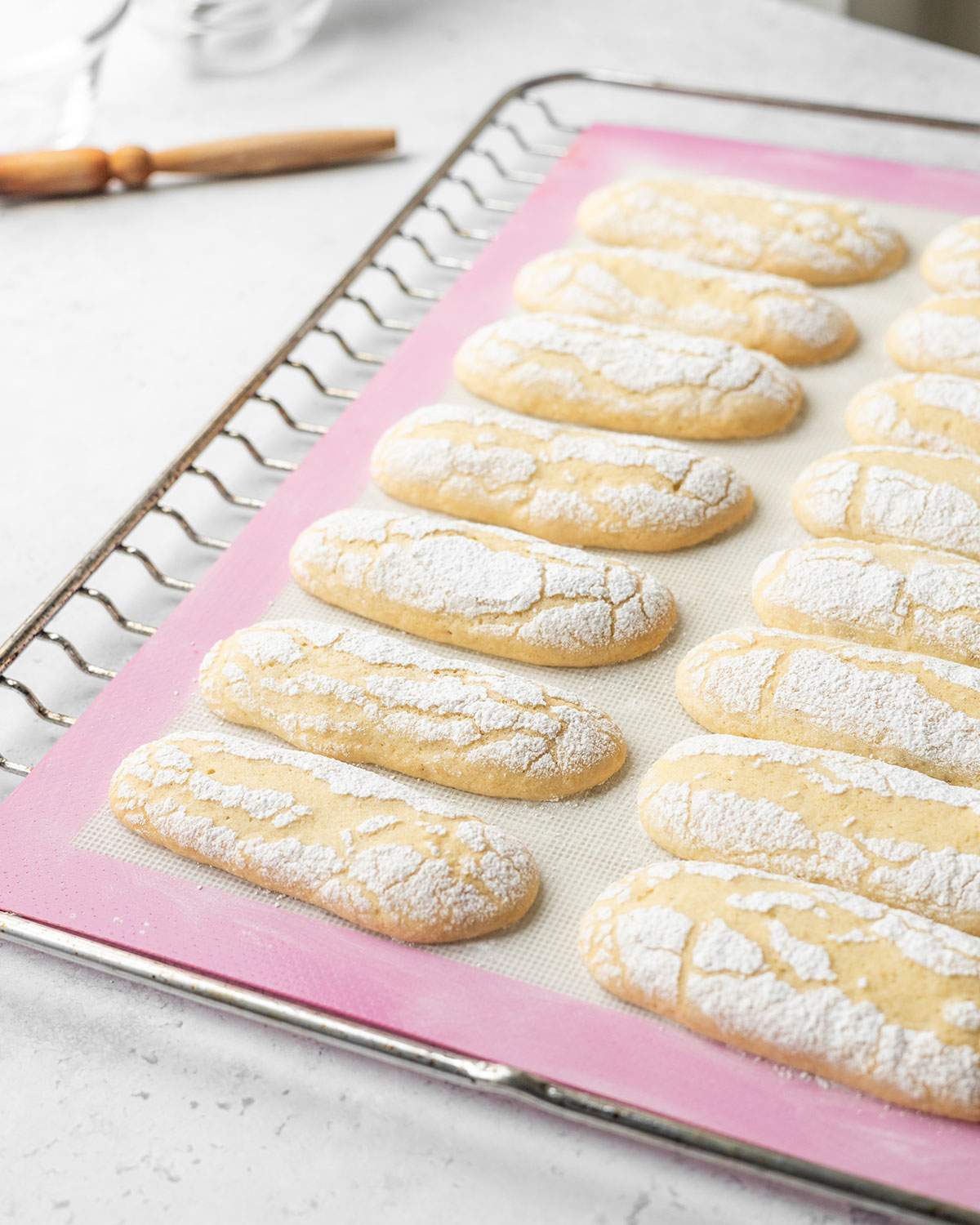 Freshly baked vegan ladyfinger biscuits on a tray.