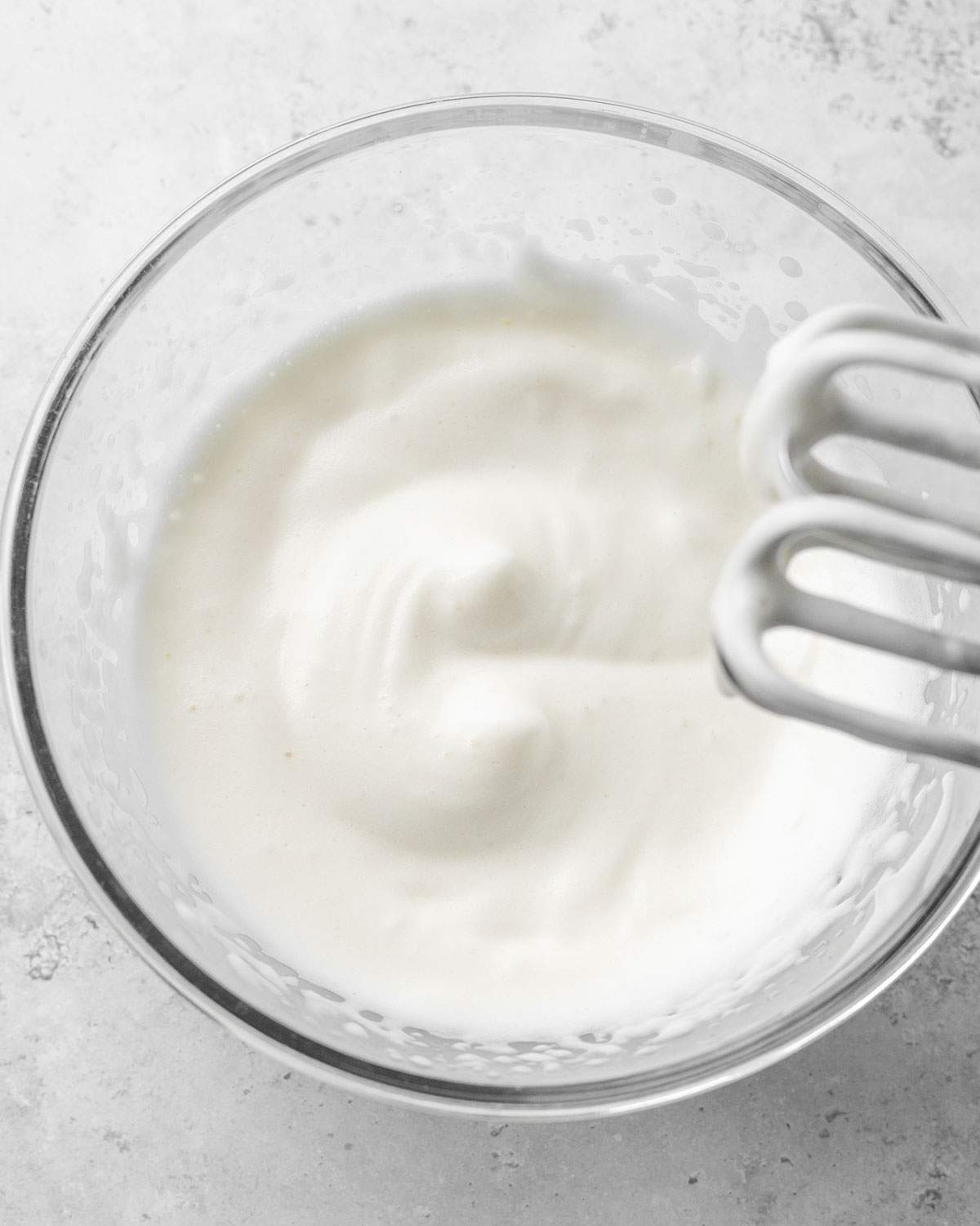 Whipped aquafaba with stiff peaks in a mixing bowl.