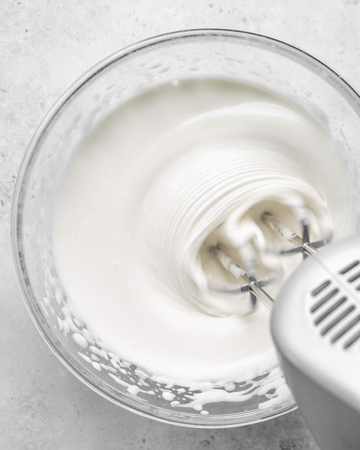 Whipping wet ingredients for vegan ladyfingers in a mixing bowl.