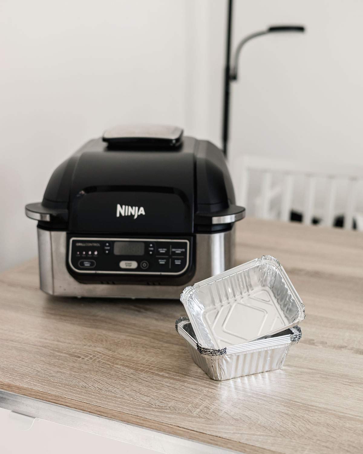 Aluminum pans in front of an air fryer on the kitchen counter.