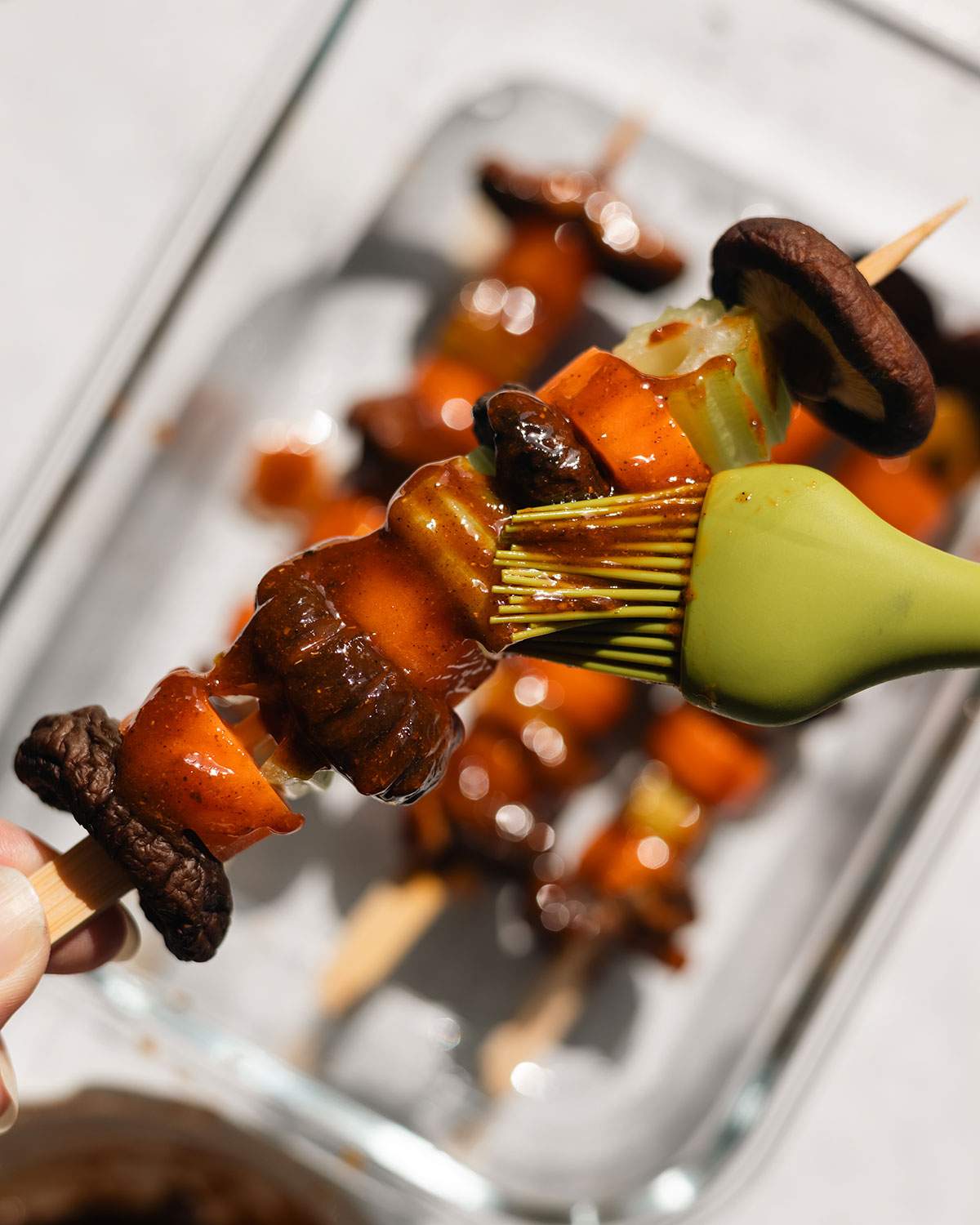 Brushing vegetables on a skewer with marinade.
