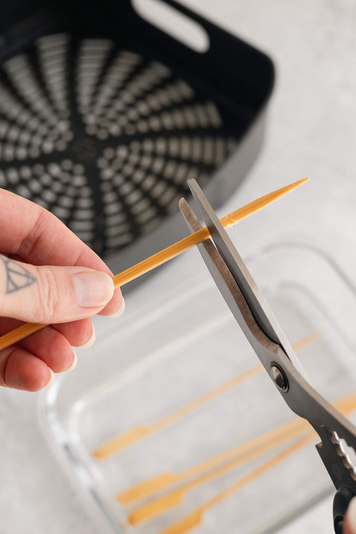 Cutting wood skewers with scissors to fit the air fryer basket.