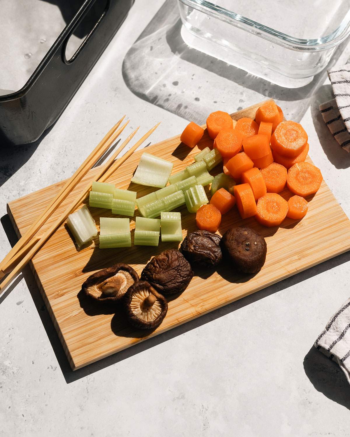 Chopped vegetables and wood skewers on a cutting board.