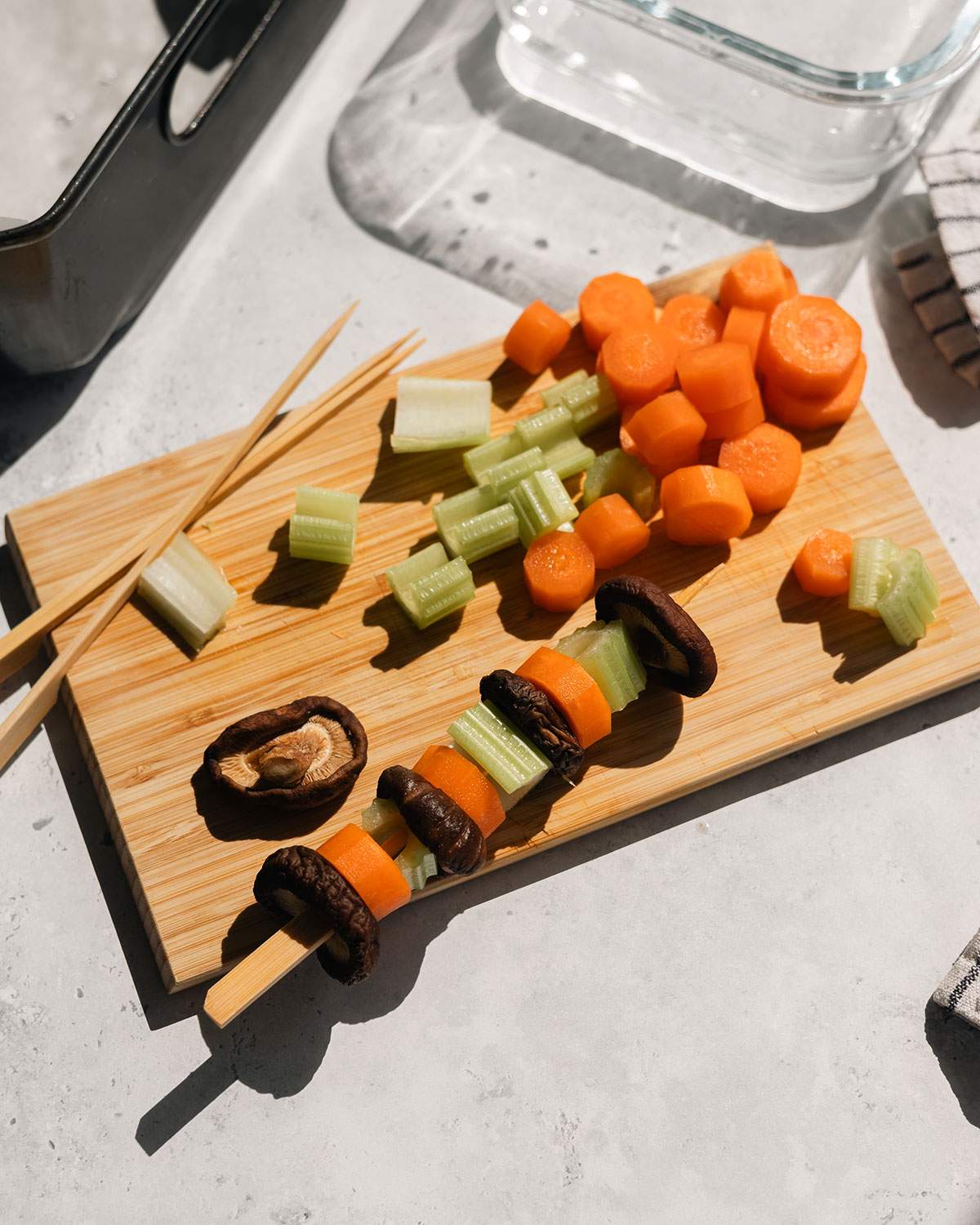Chopped vegetables being added to wood skewers.
