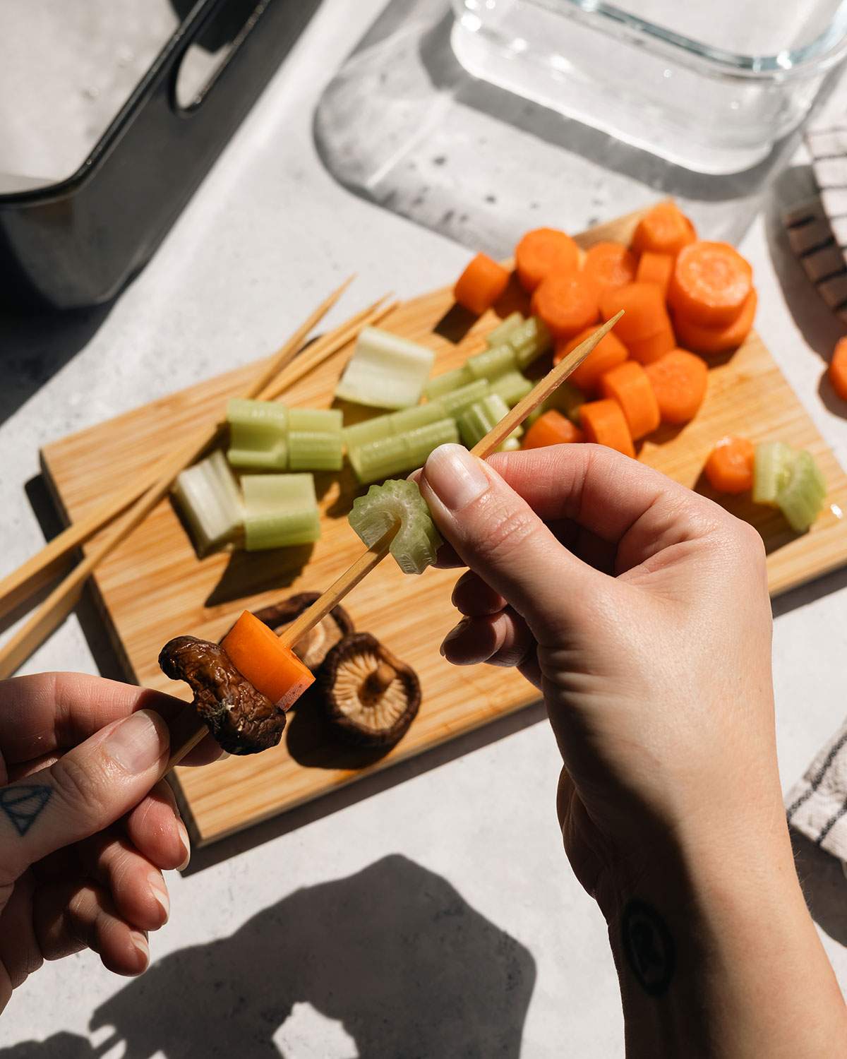 Chopped vegetables being added to wood skewers.