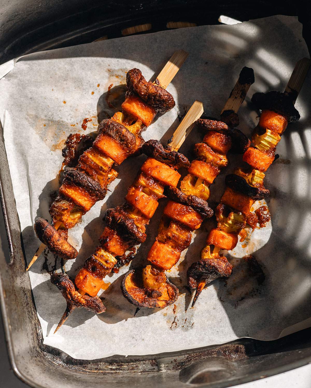 Cooked vegetables on wood skewers in the air fryer basket.