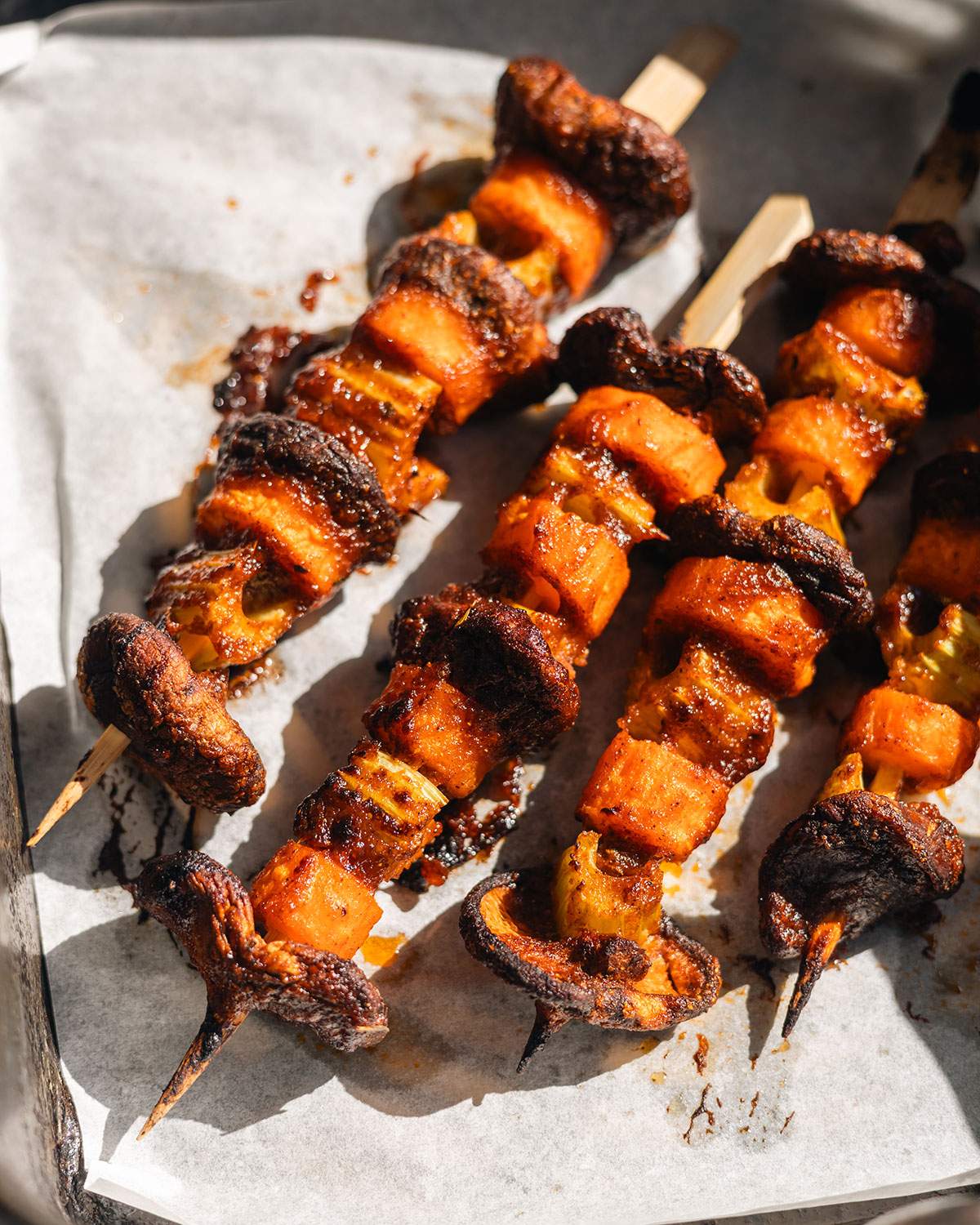 Cooked vegetables on wood skewers in the air fryer basket.