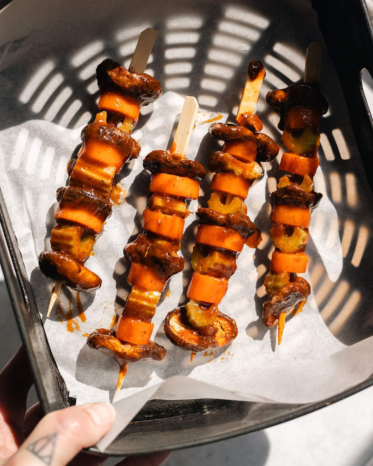 Uncooked vegetables on wood skewers in the air fryer basket.