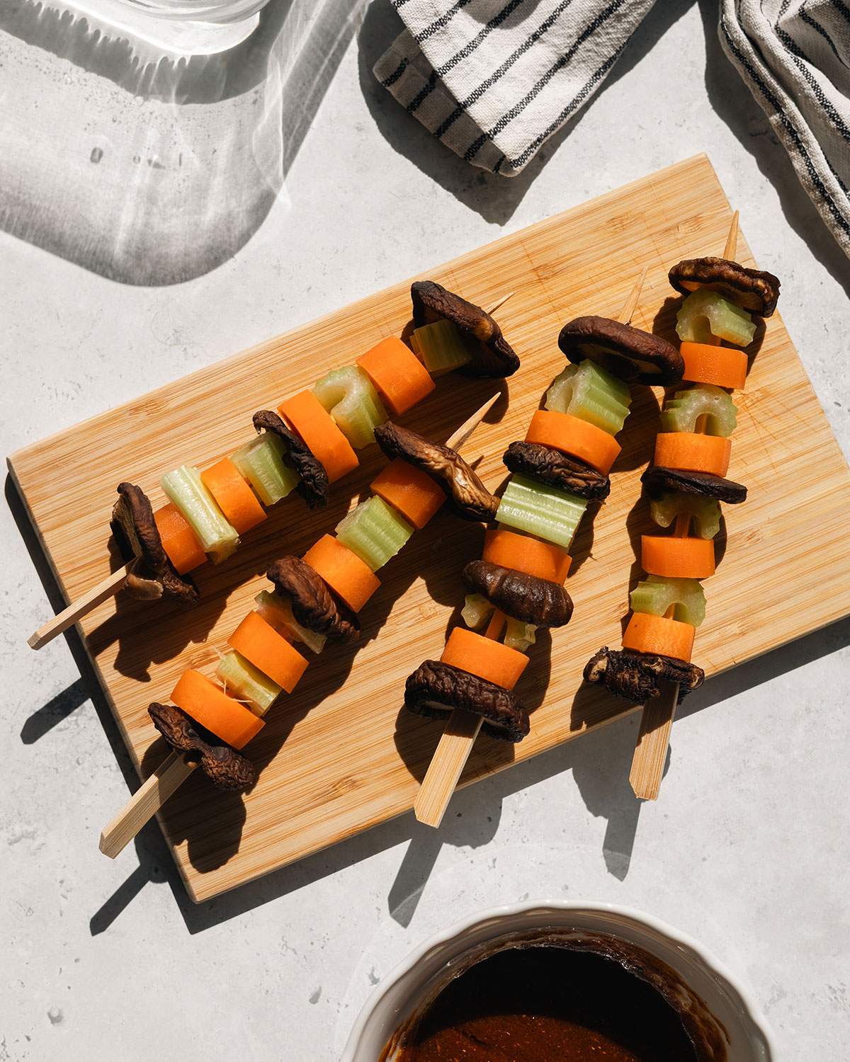 Vegetables on wooden skewers on a cutting board.