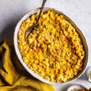 A serving dish with vegan creamed corn and a spoon on the side.