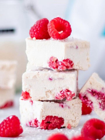 Three frozen yogurt protein bars with raspberries stacked on top of each other.