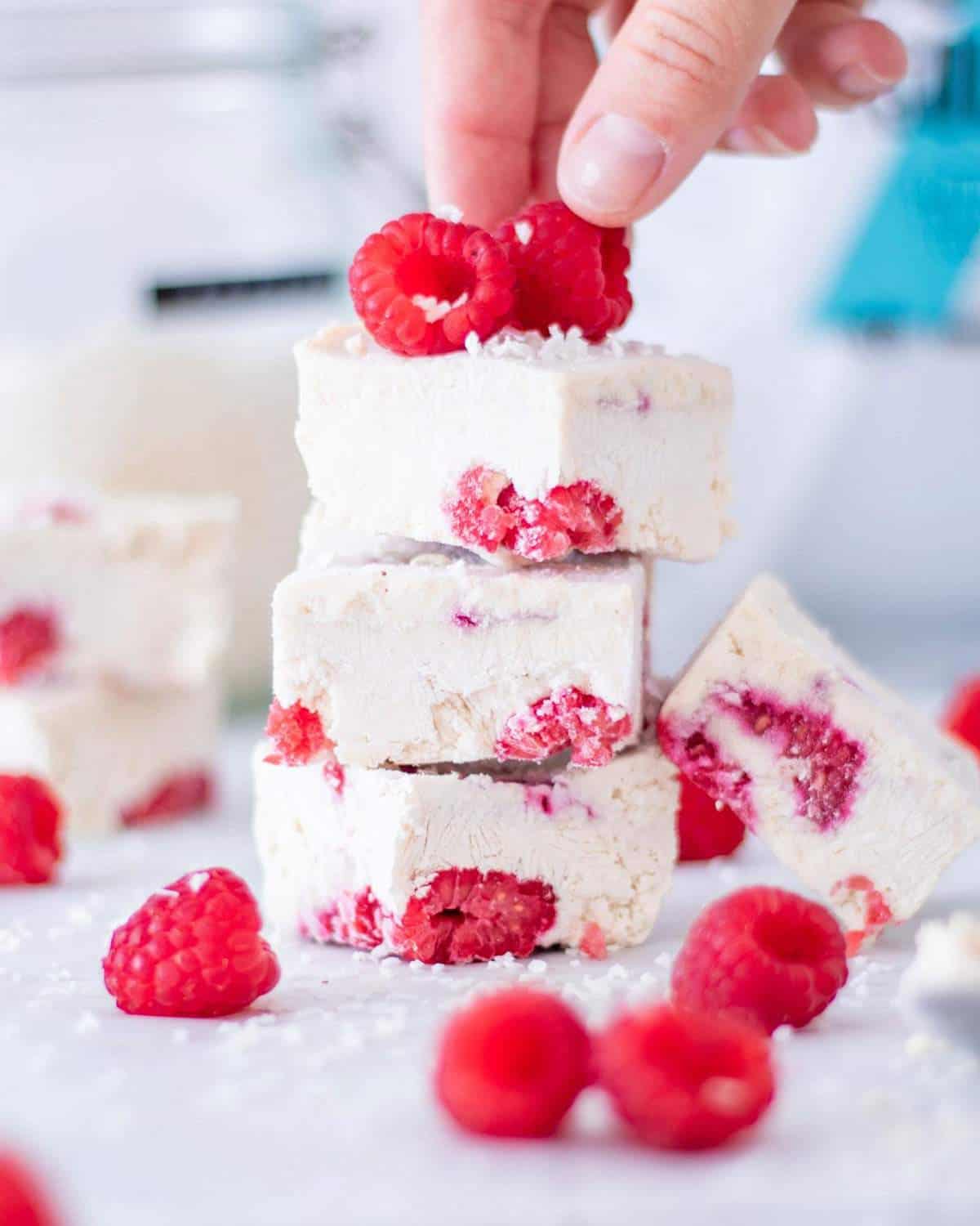 Three vegan frozen yogurt protein bars with raspberries stacked on top of each other.