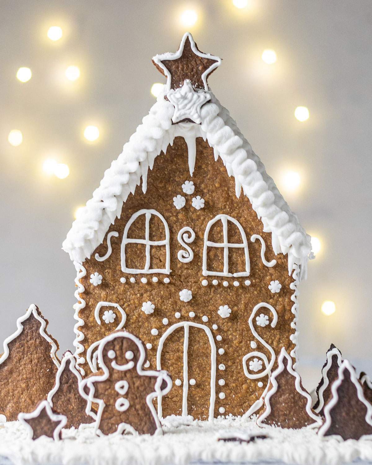 A Vegan Gingerbread House decorated with vegan icing in a wintery scene.