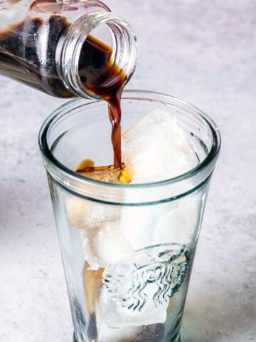 Pouring coffee into a tall glass with ice.