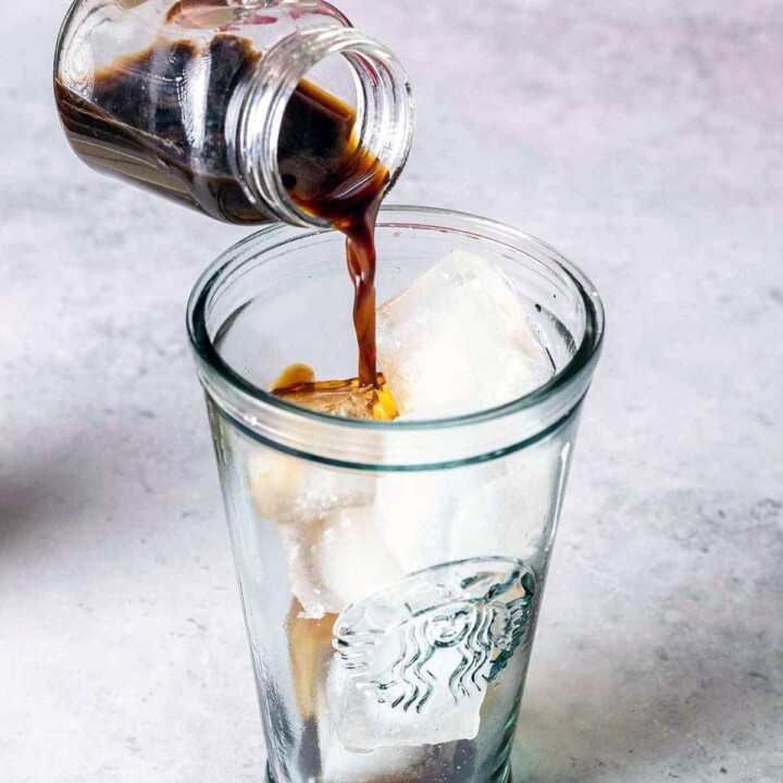 Pouring coffee into a tall glass with ice.