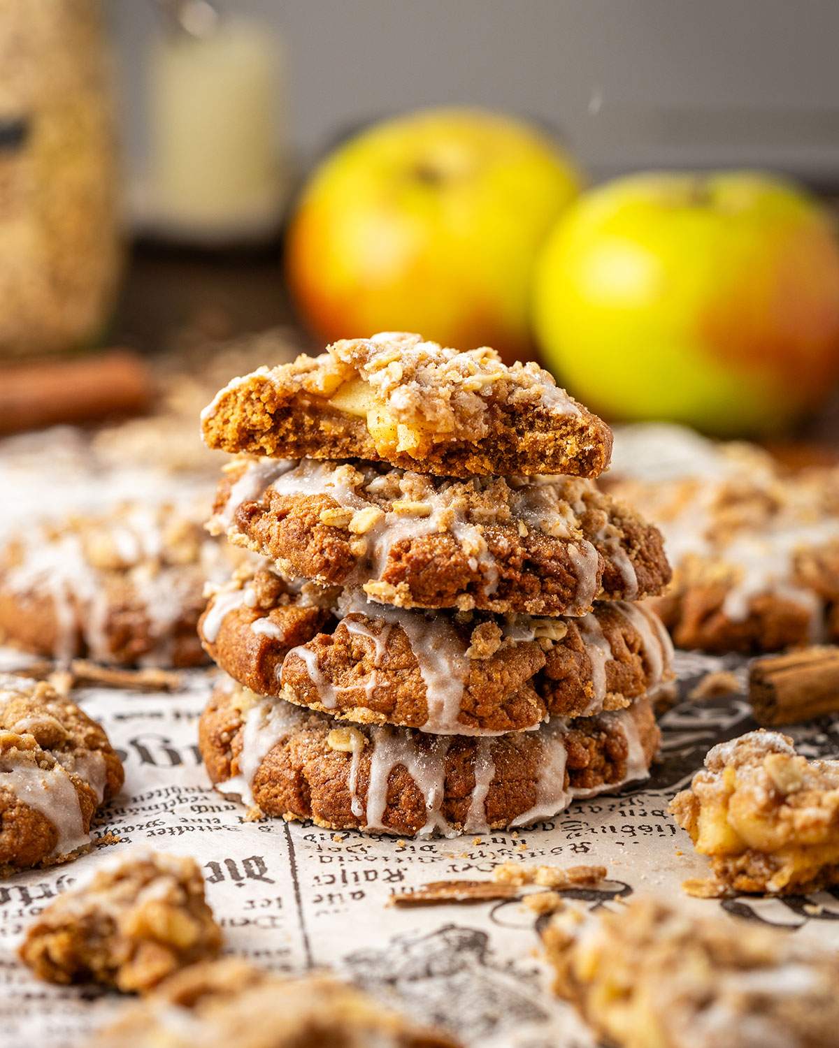 Four stacked apple cookies with glaze, and a bite taken out of the cookie on top, showing the apple filling.