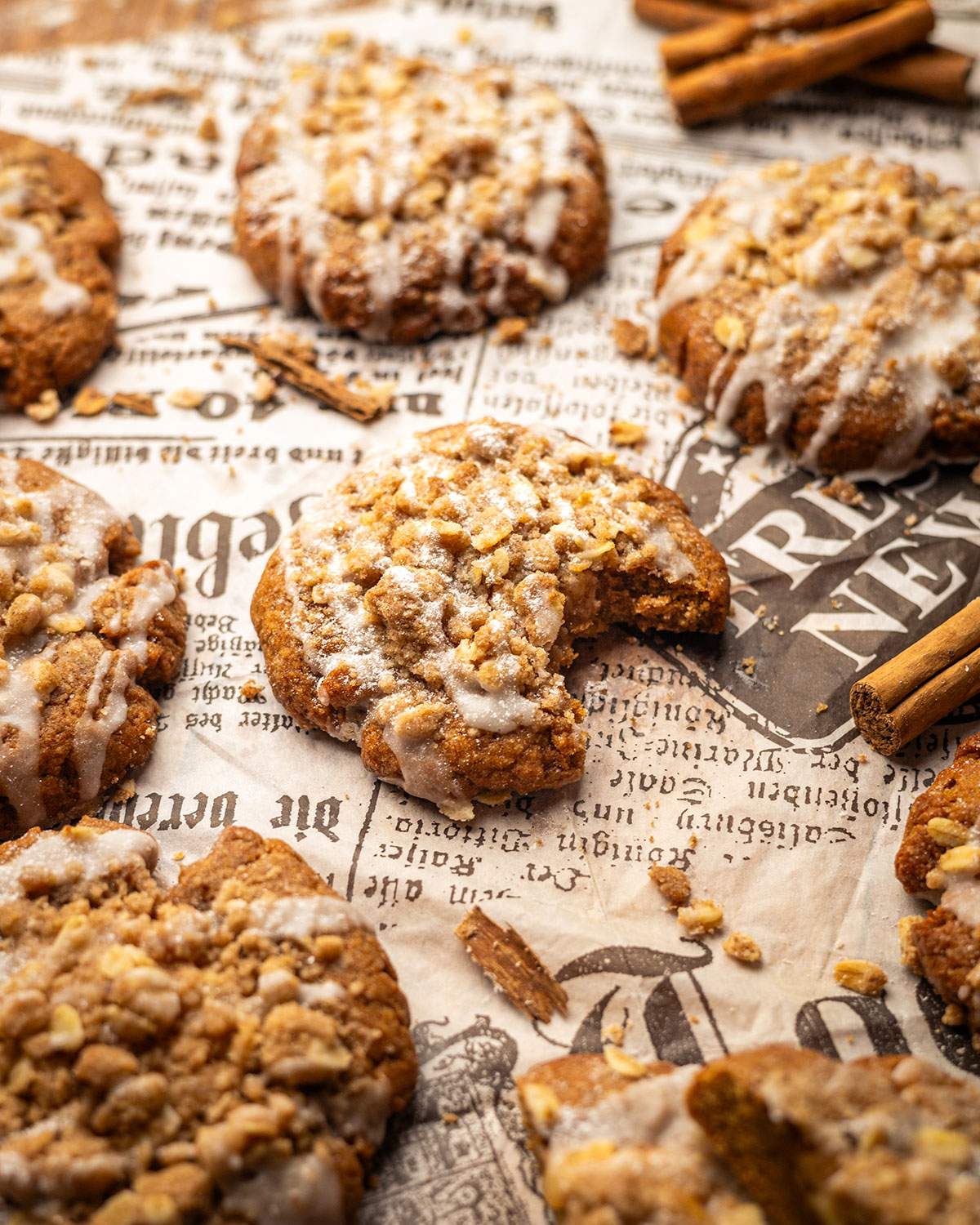 A bite taken out of an apple crumble cookie on parchment paper.
