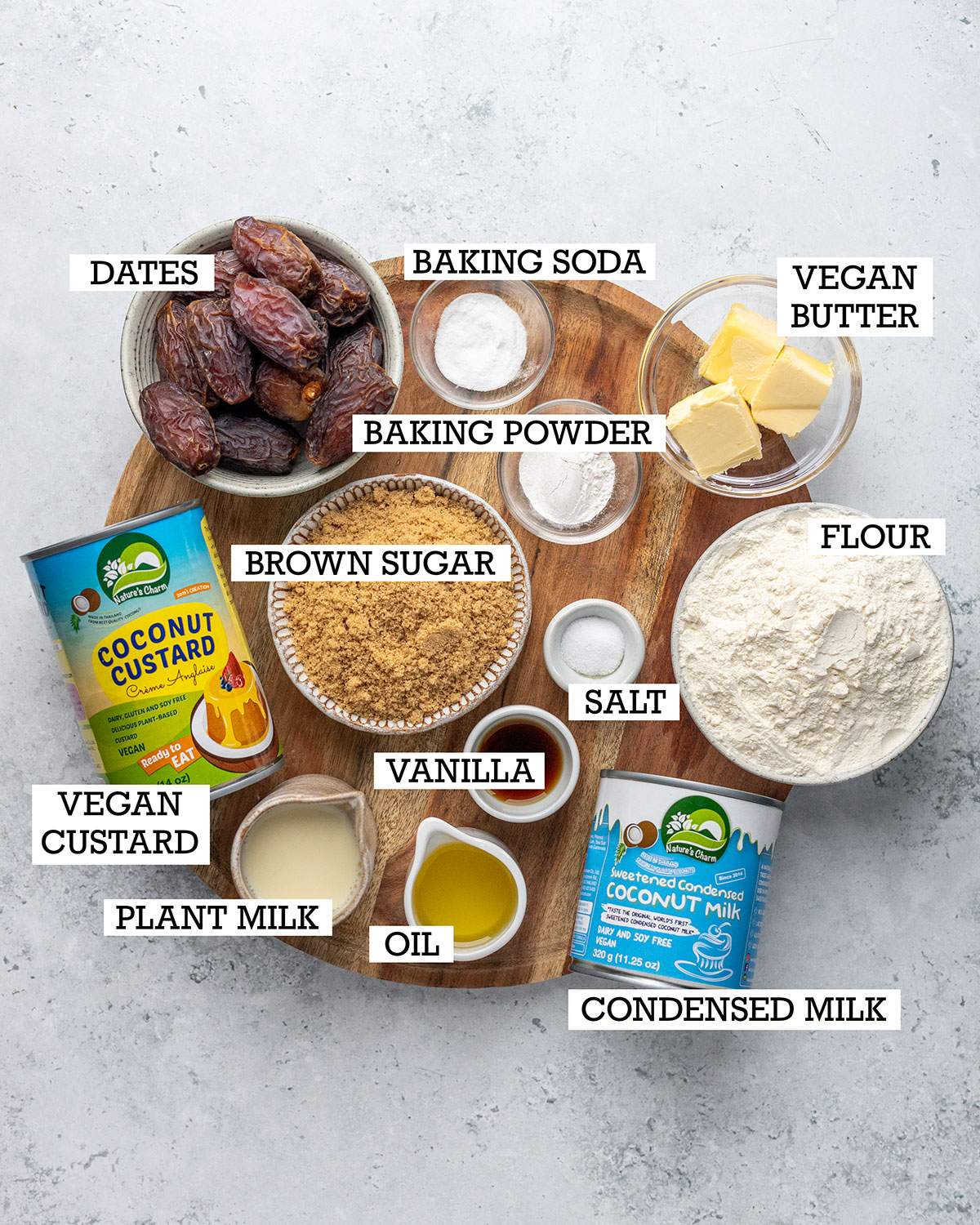 Ingredients for vegan sticky toffee pudding on a wooden board with labels.