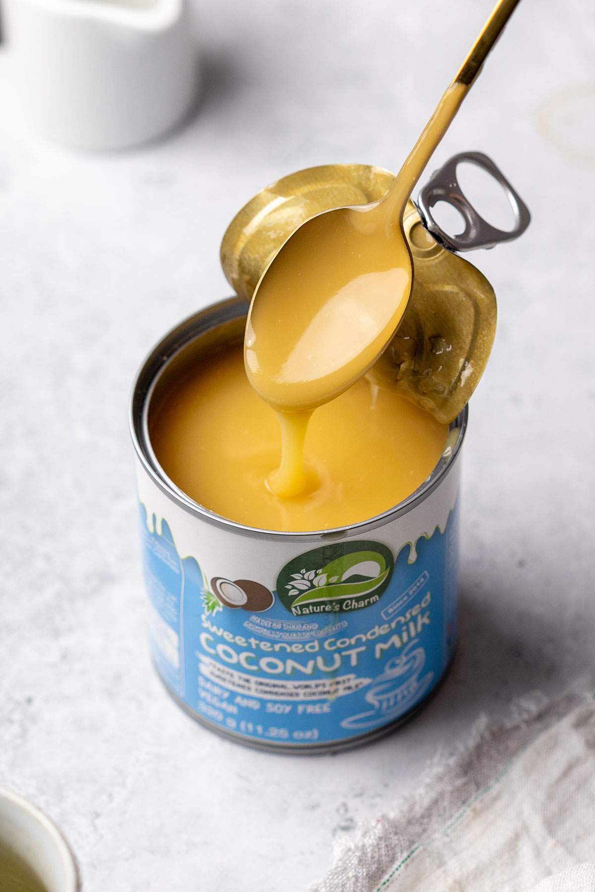 A spoon lifting thick coconut condensed milk from a can.