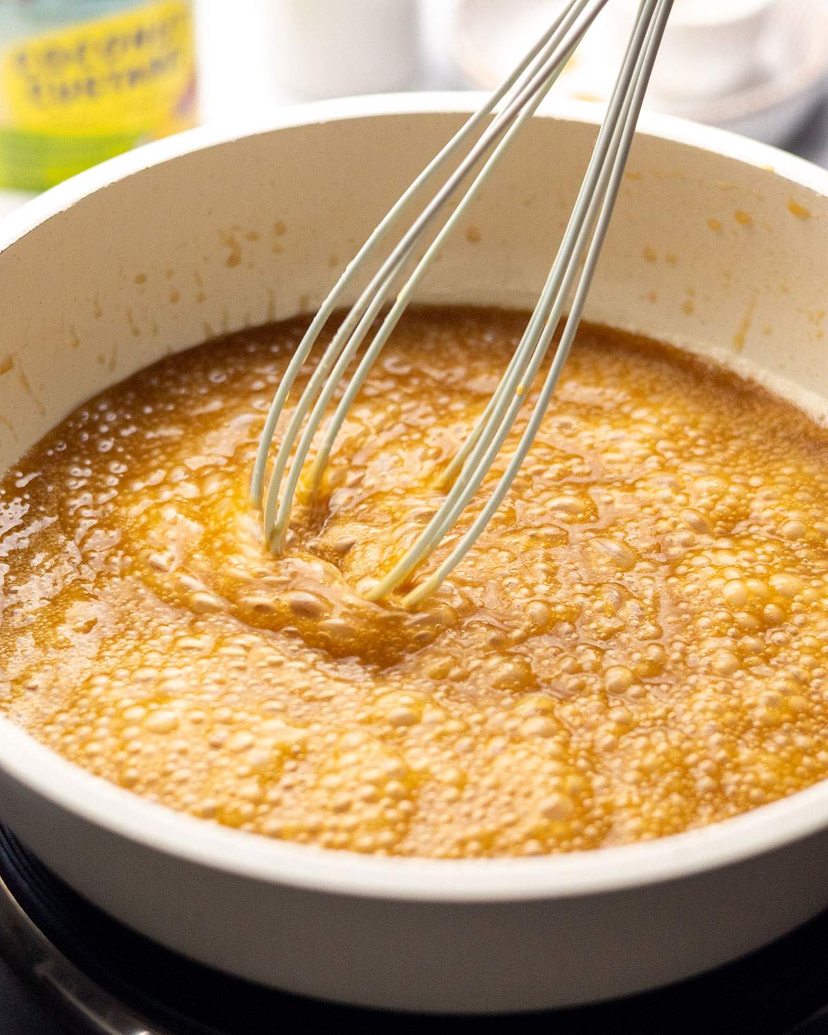 Whisking sticky toffee pudding sauce in a mixing bowl.