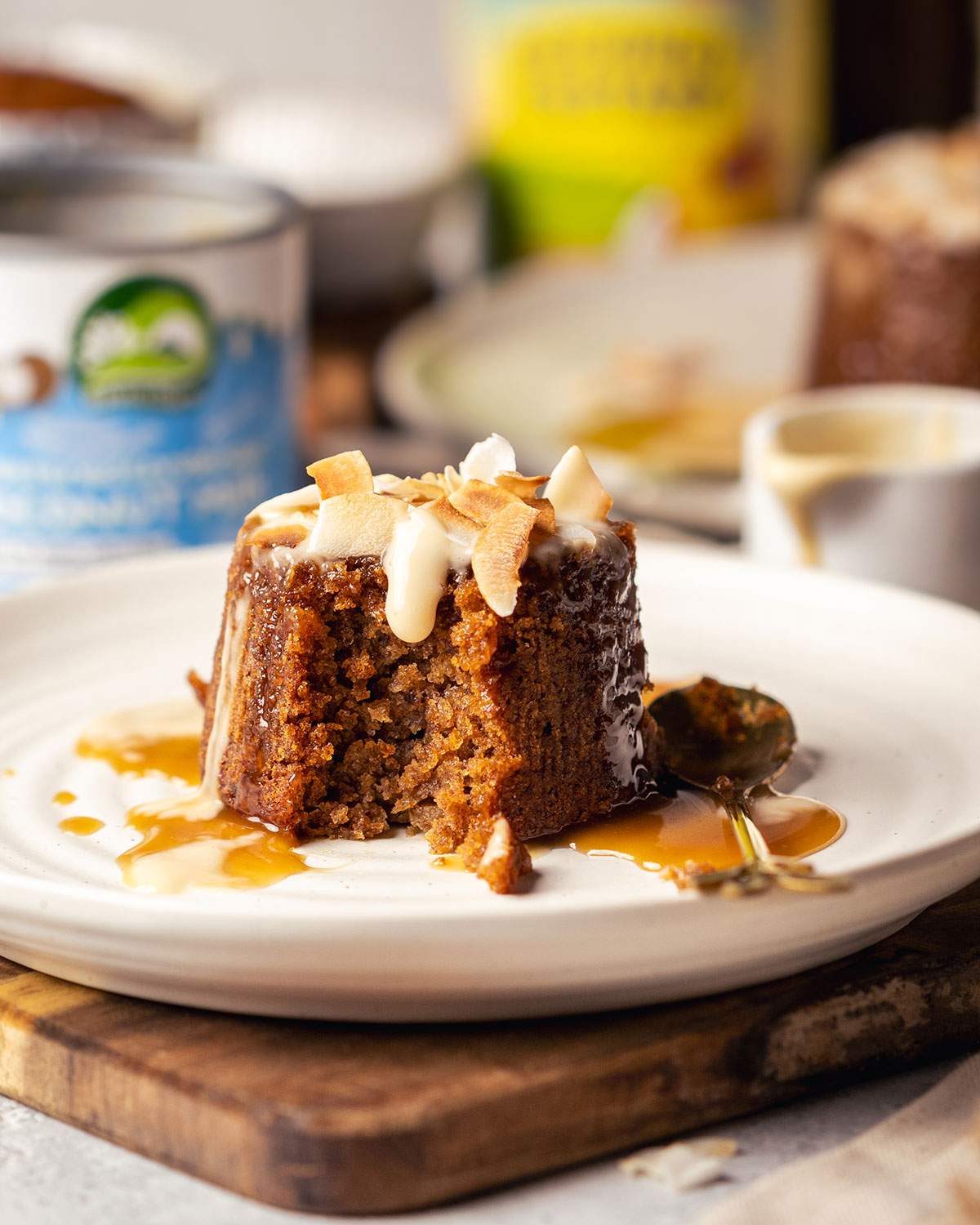 Sticky toffee pudding drizzled with warm custard on a plate.