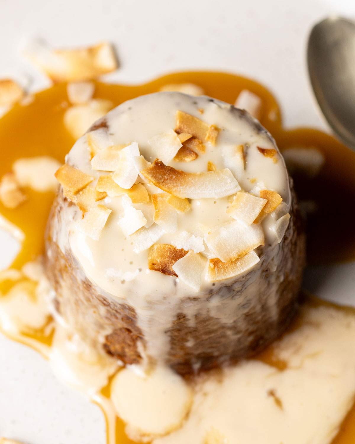 Sticky toffee pudding topped with coconut flakes and sauce.