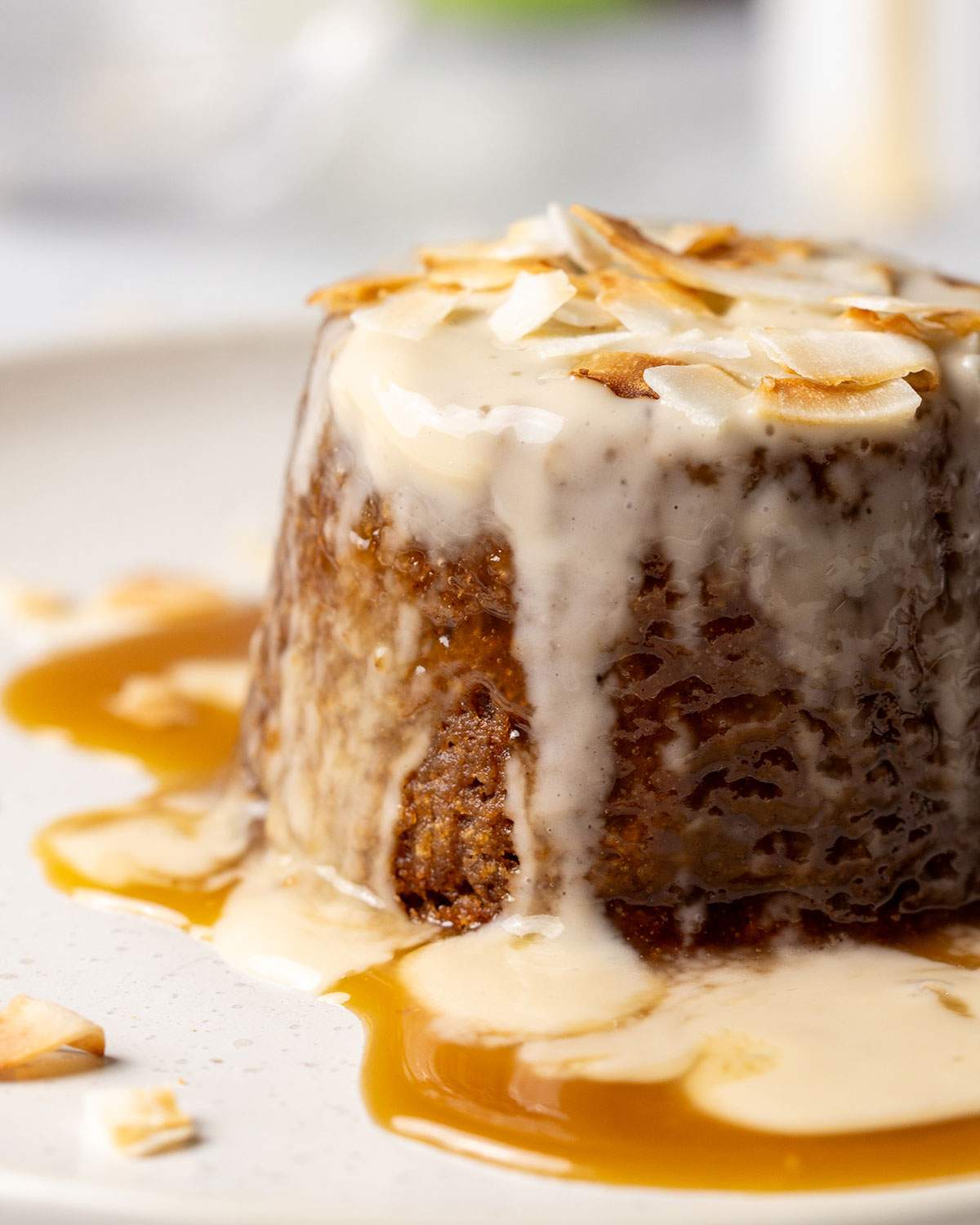 Close-up of sticky toffee pudding covered in custard and sauce.
