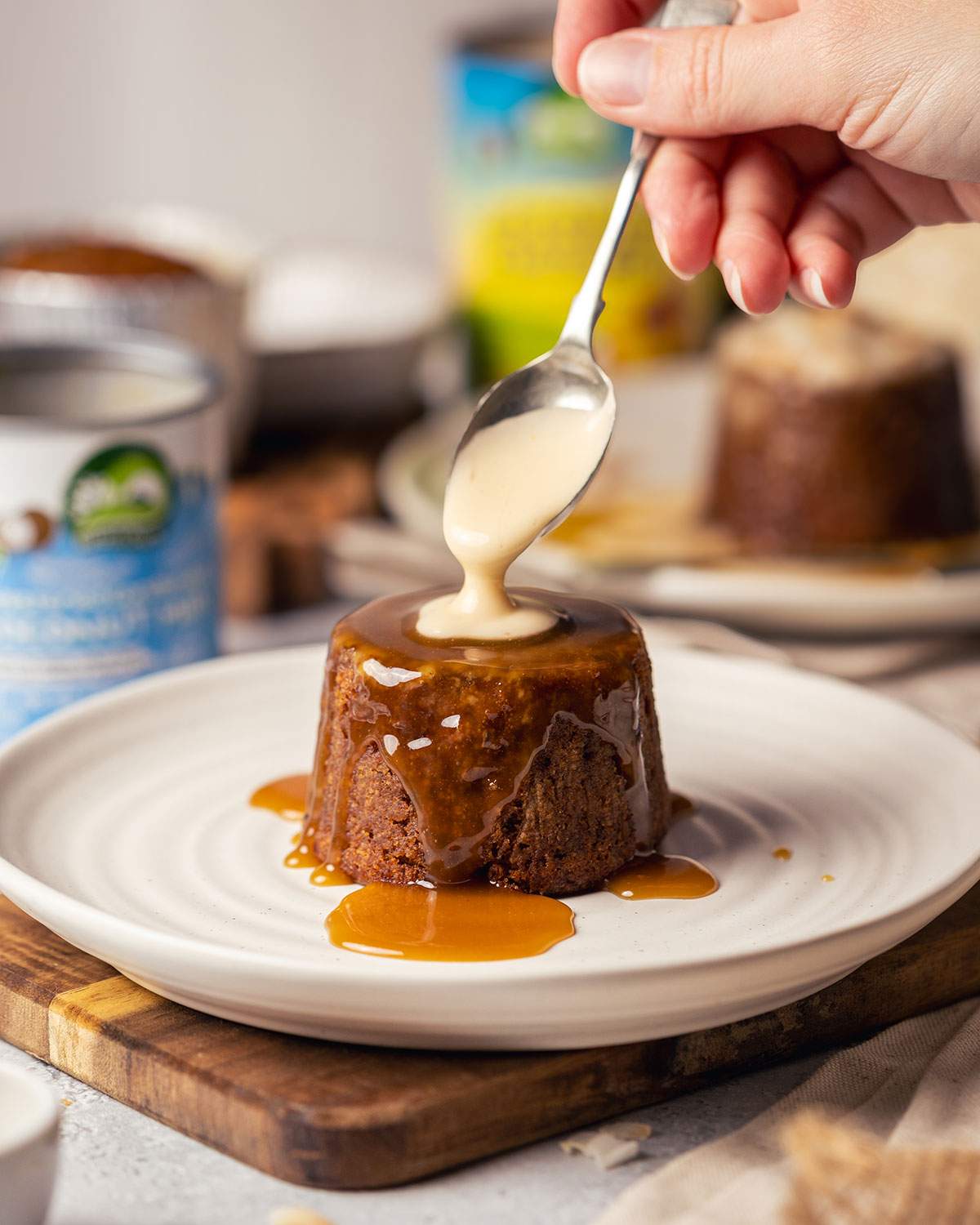 Pouring coconut custard over a warm sticky toffee pudding.