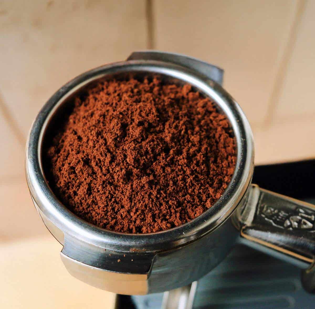 Fresh coffee grounds close up in portafilter.