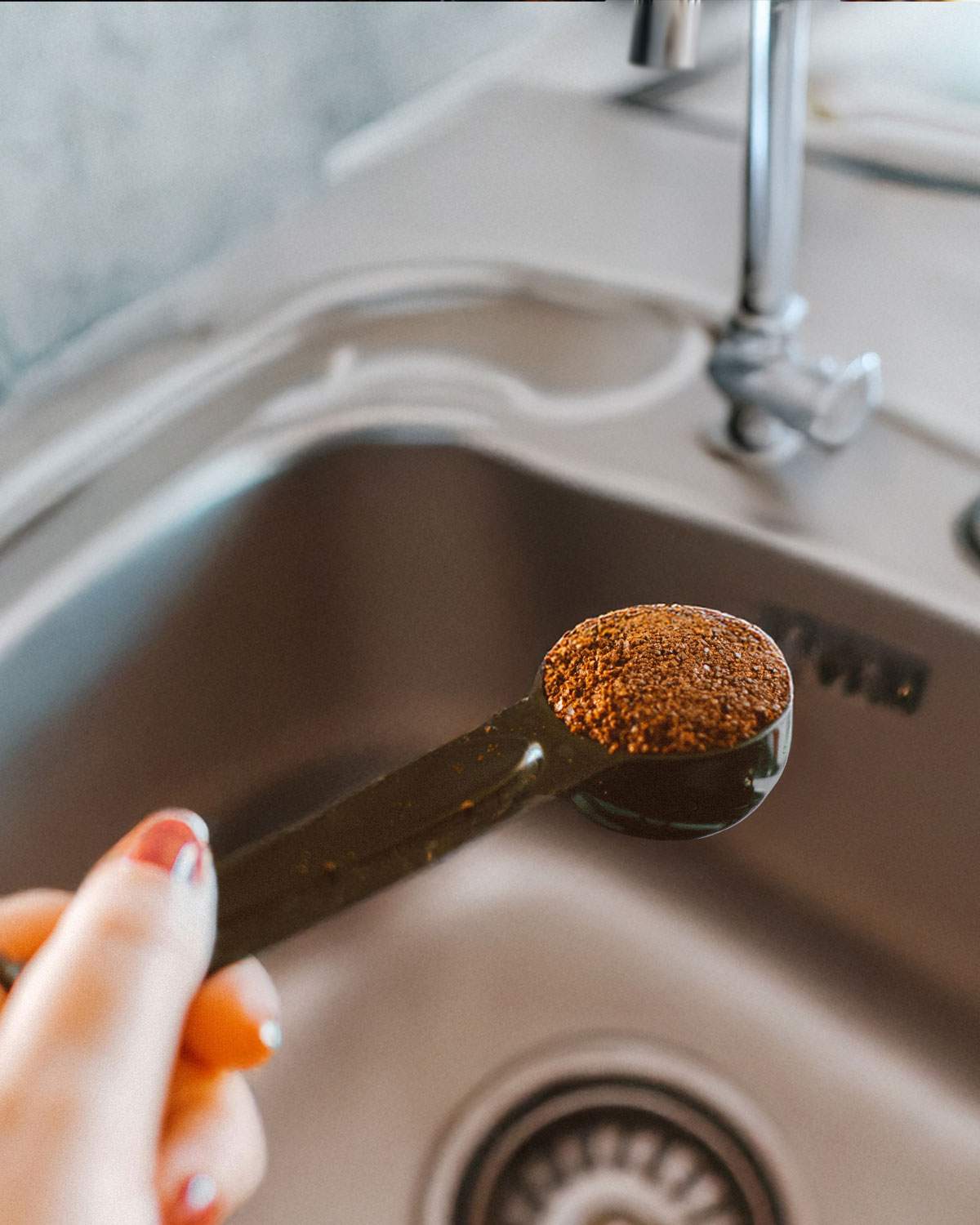 Coffee grounds being held over the kitchen sink.