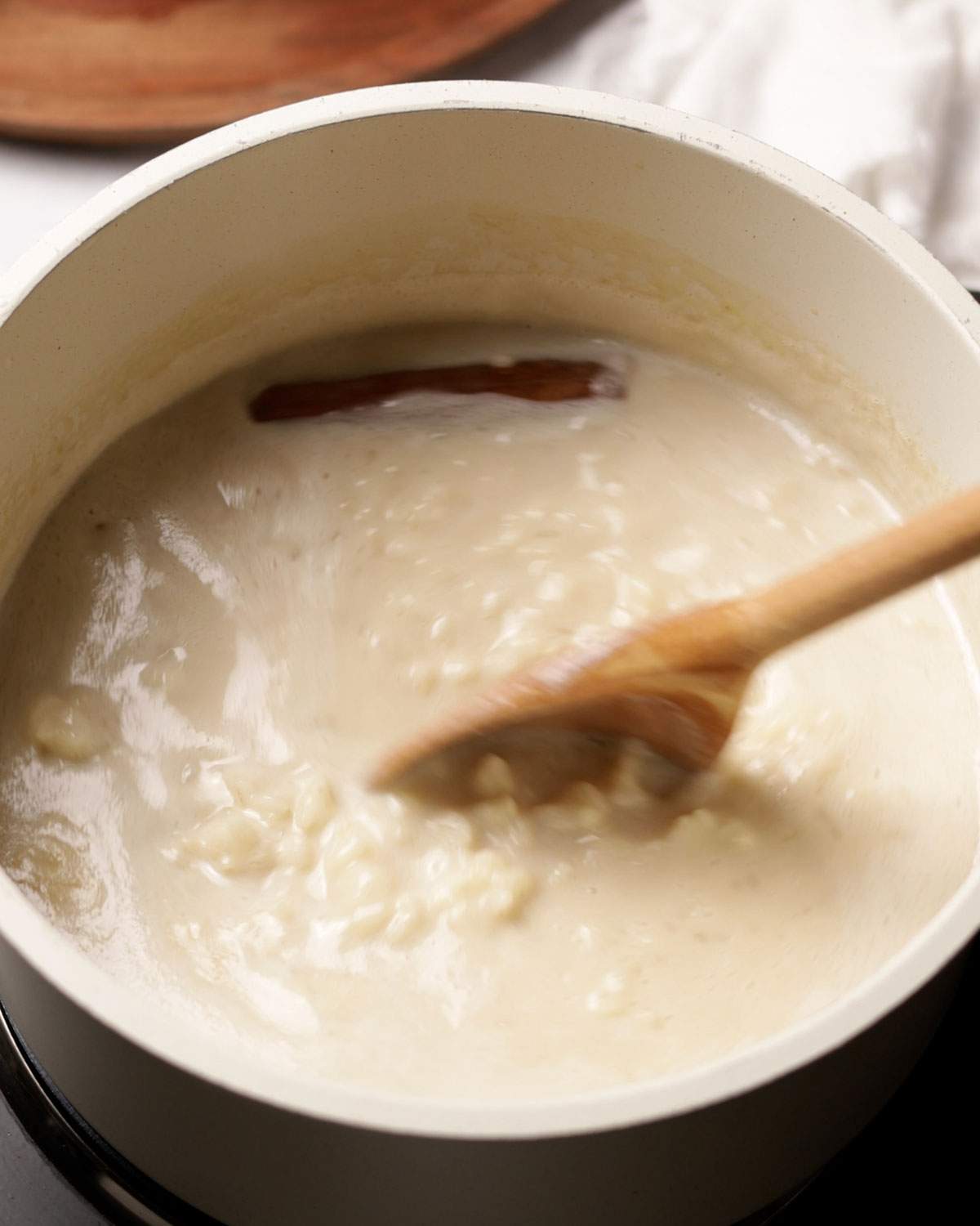 Stirring vegan rice pudding in a saucepan.