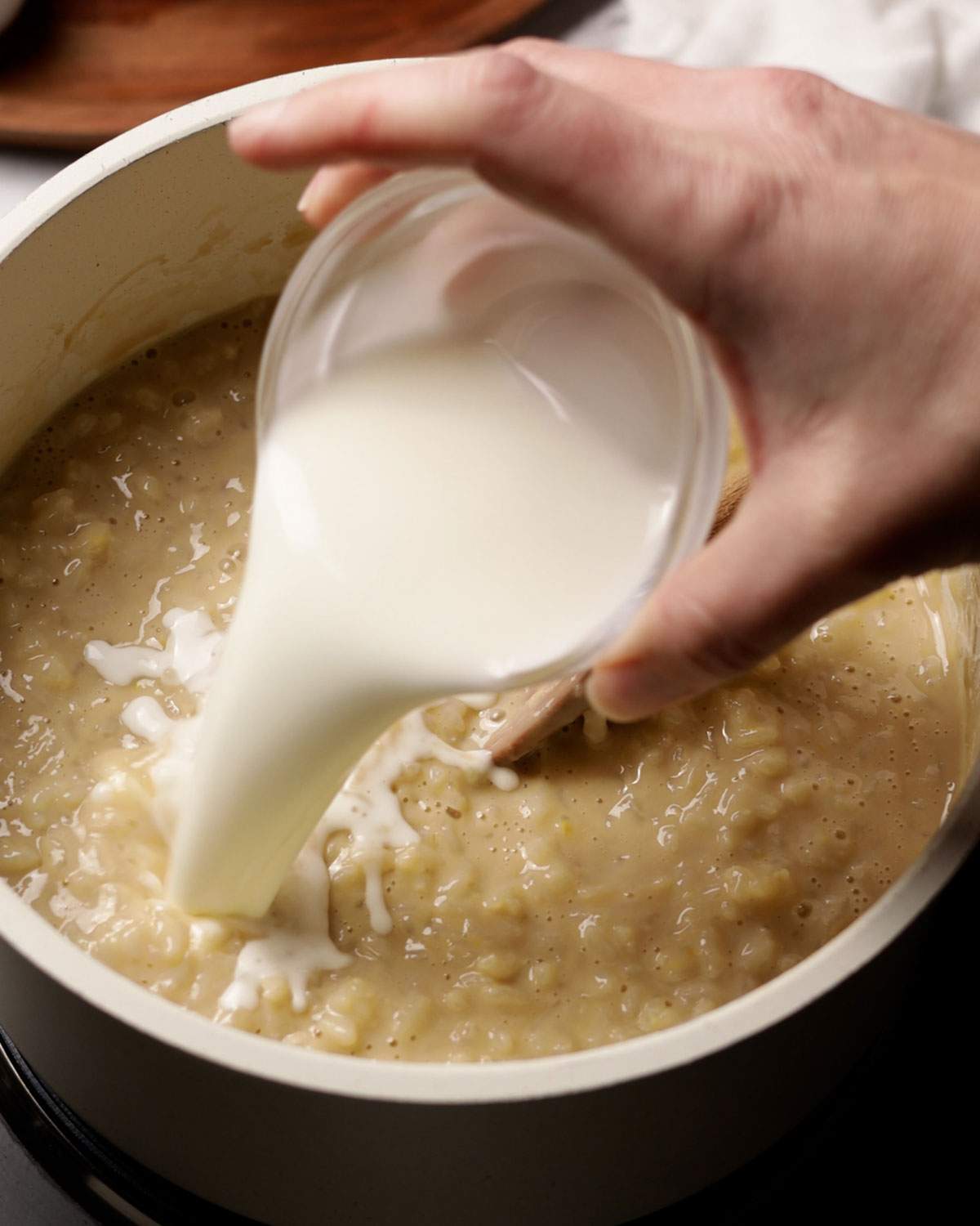 Pouring cornstarch slurry into rice pudding.